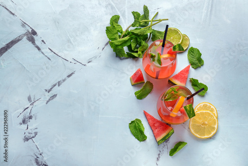Glasses of tasty cold watermelon lemonade and mint on color background