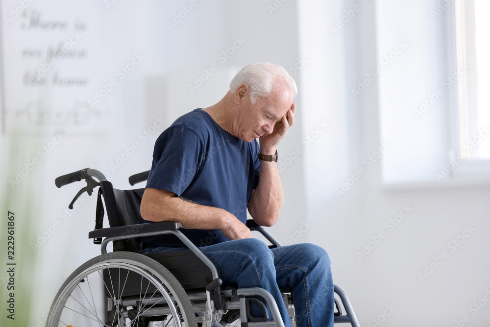 Disabled senior man in wheelchair suffering from headache at home Disabled senior man in wheelchair suffering from headache at home