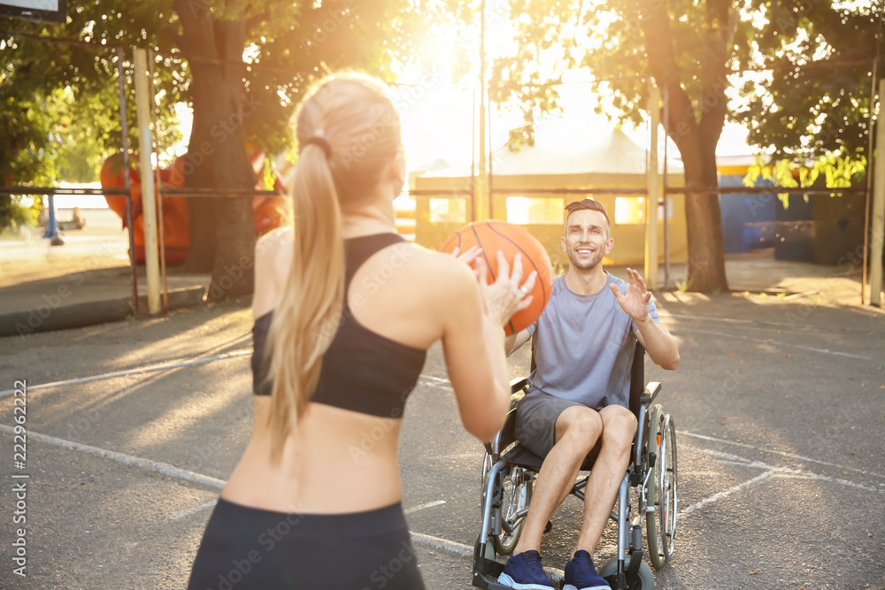 Φωτογραφία Young man in wheelchair and sporty woman training with ball outdoors