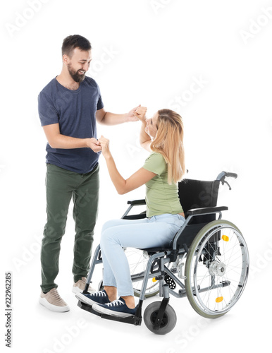 Beautiful woman in wheelchair with man dancing on white background