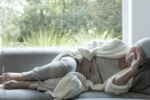 Sick woman with a headache lying on a sofa photo