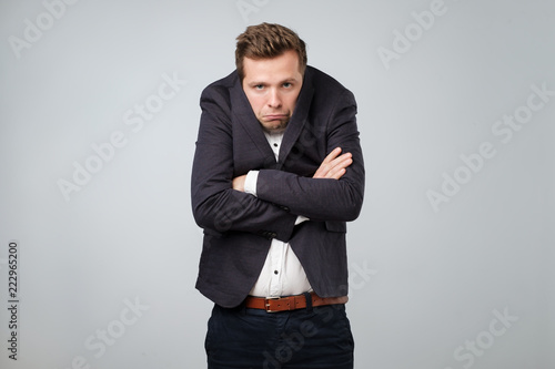 Caucasian young man in too big suit. He is offended and looking stressed. photo