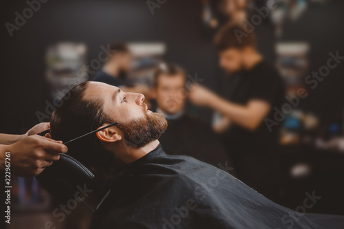 Man sitting in armchair barbershop, barber is getting ready to cut his hair.