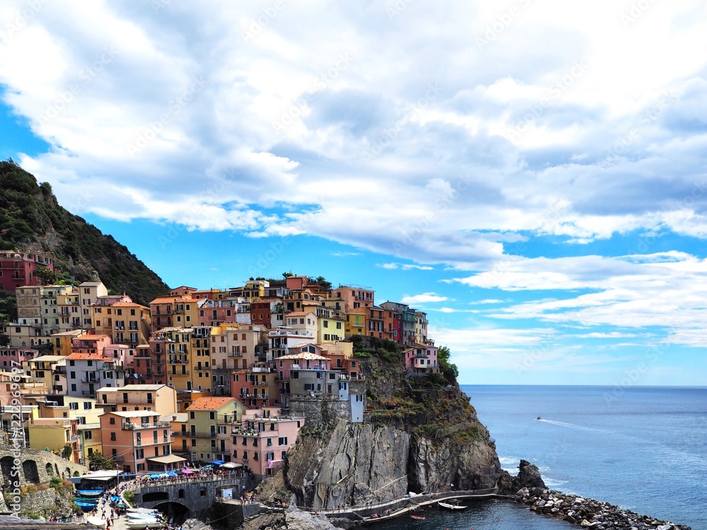 Panorama of the city of Manarola in the province of Cinque Terre in Italy, a cozy colorful place, colorful houses are located on a hill above the sea, down the Bay with boats