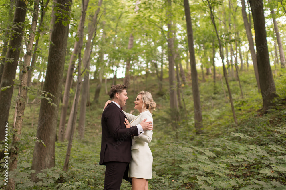 Embracing adult newlyweds in green woods Embracing adult newlyweds in green woods