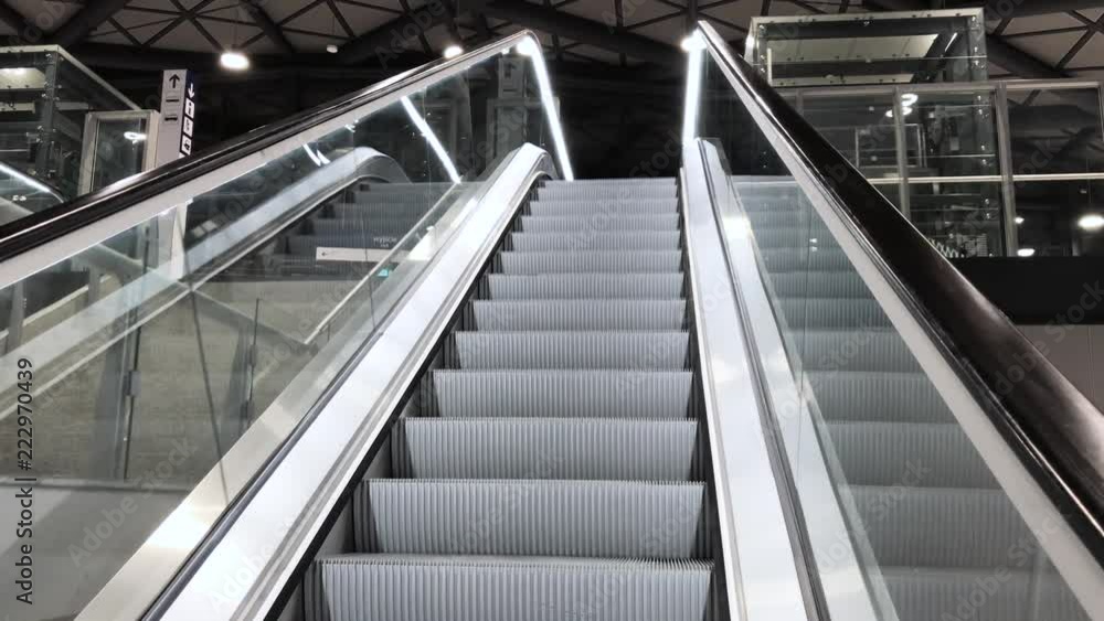 Wide view of moving stairs escalator descending in airport, station or shopping mall, architecture detail shot in 4K UHD Wide view of moving stairs escalator descending in airport, station or shopping mall, architecture detail shot in 4K UHD
