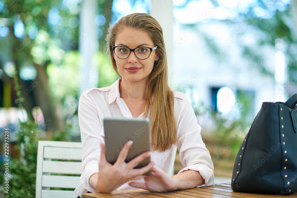 Businesswoman using technologies outdoor while sitting on the bench.