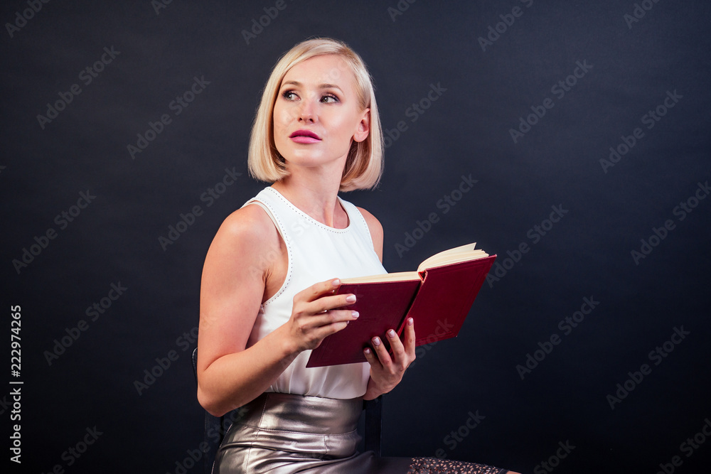 woman reading in a notebook in studio on a black background woman reading in a notebook in studio on a black background