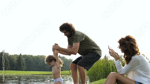 Wallpaper Mural Father playing with his little daughter near the pond, while mother taking photos and videos on the smartphone. Steadycam shot. Torontodigital.ca