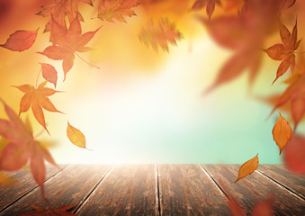 Autumn season backdrop with falling tree leaves and a wooden table.