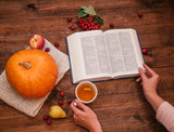 Top view of girl's hand on a table,a  pumpkin, apples and a book, phone on wooden table.