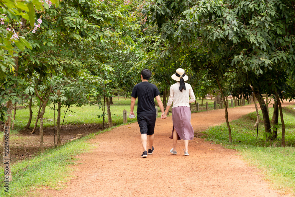 Young asian couple hand holding hand walking in the woods in summer. Young asian couple hand holding hand walking in the woods in summer.