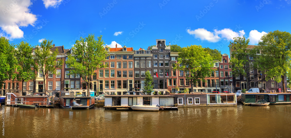 Beautiful panoramic linear panorama of the Nieuwe keizersgracht canal  in Amsterdam, the Netherlands, on a sunny summer day with a blue sky and clouds