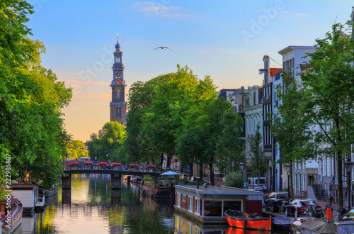 UNESCO world heritage Prinsengracht canal with the Westerkerk (Western church) on a summer morning with a blue sky in Amsterdam, The Netherlands

