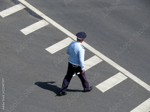 Policeman with a traffic rod in his hands. Russian police officer walking on an empty road, traffic cop