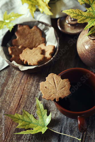 Autumn mood. Cinnamon cookies in form of maple leaves, cup of coffee and yellow leaves. Toned image © photosimysia