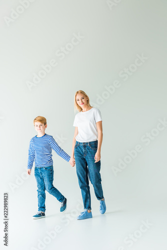 mother and son holding hands on white and looking at camera