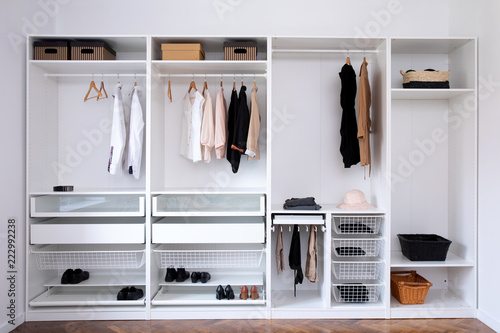 clothes hanging on rail in white wardrobe 