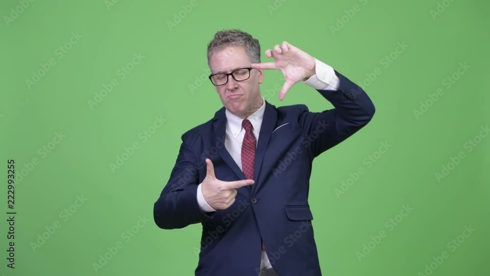 Studio shot of mature businessman focusing with fingers Studio shot of mature businessman focusing with fingers