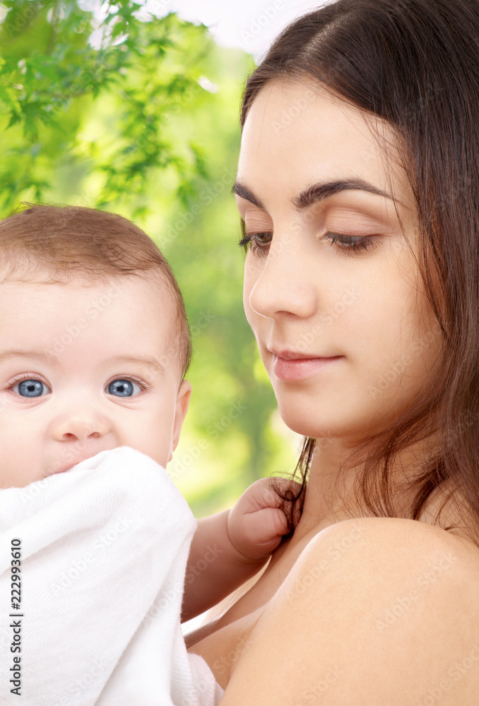 family and motherhood concept - happy smiling young mother with little baby over green natural background family and motherhood concept - happy smiling young mother with little baby over green natural background