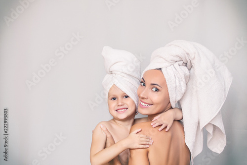 Woman young adult with daughter after shower in fresh towels hugging on isolated background