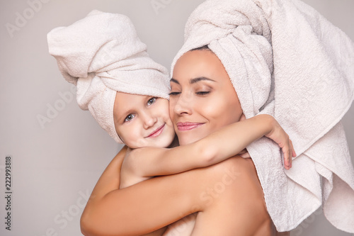 Woman young adult with daughter after shower in fresh towels hugging on isolated background