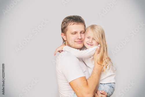 Father with a little daughter in his arms laughing happy and playing on a gray background in the Studio