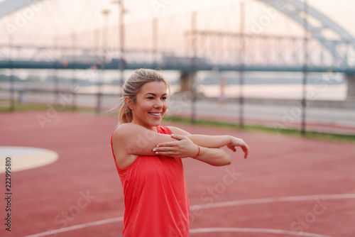 Beautiful sporty blond girl stretching her muscles after hard training outside. photo