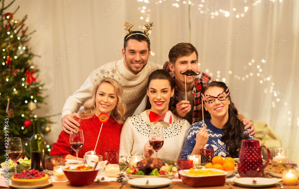holidays and celebration concept - happy friends with party props having christmas dinner at home holidays and celebration concept - happy friends with party props having christmas dinner at home