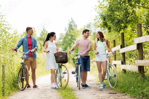 people, leisure and lifestyle concept - happy young friends with fixed gear bicycles on country road in summer #223003280