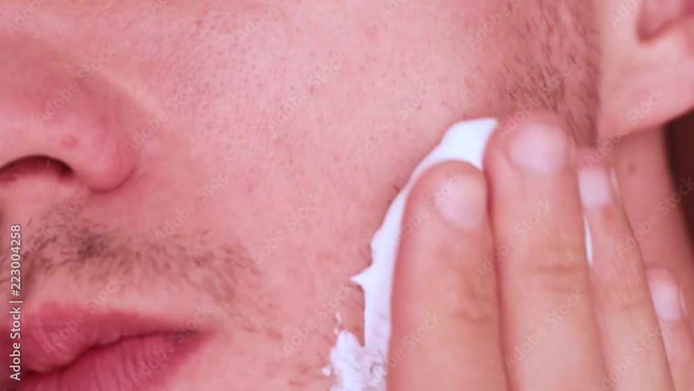 the guy is applying a gel to shave his beard the guy is applying a gel to shave his beard