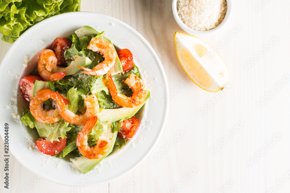 Fresh Caesar shrimp salad with delicious prawns, ruccola, spinach, cabbage, arugula, egg, parmesan and cherry tomato on wooden background. Oil, salt and pepper. Healthy and diet food concept. Fresh Caesar shrimp salad with delicious prawns, ruccola, spinach, cabbage, arugula, egg, parmesan and cherry tomato on wooden background. Oil, salt and pepper. Healthy and diet food concept.