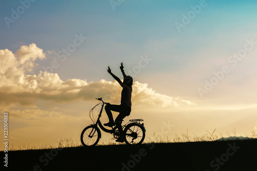 silhouette small girl riding bike in park at sunset background