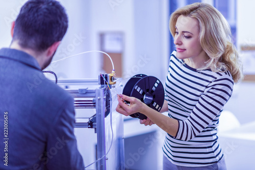 Modern engineer. Pleased young engineer standing in semi position while working with her partner photo