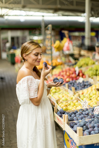 Young woman buying plums on...