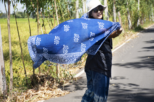 Thai women posing relax and playing indigo tie dye fabric shawl on the small street in countryside photo