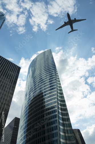 Airplane in the sky with modern buildings © flydragon