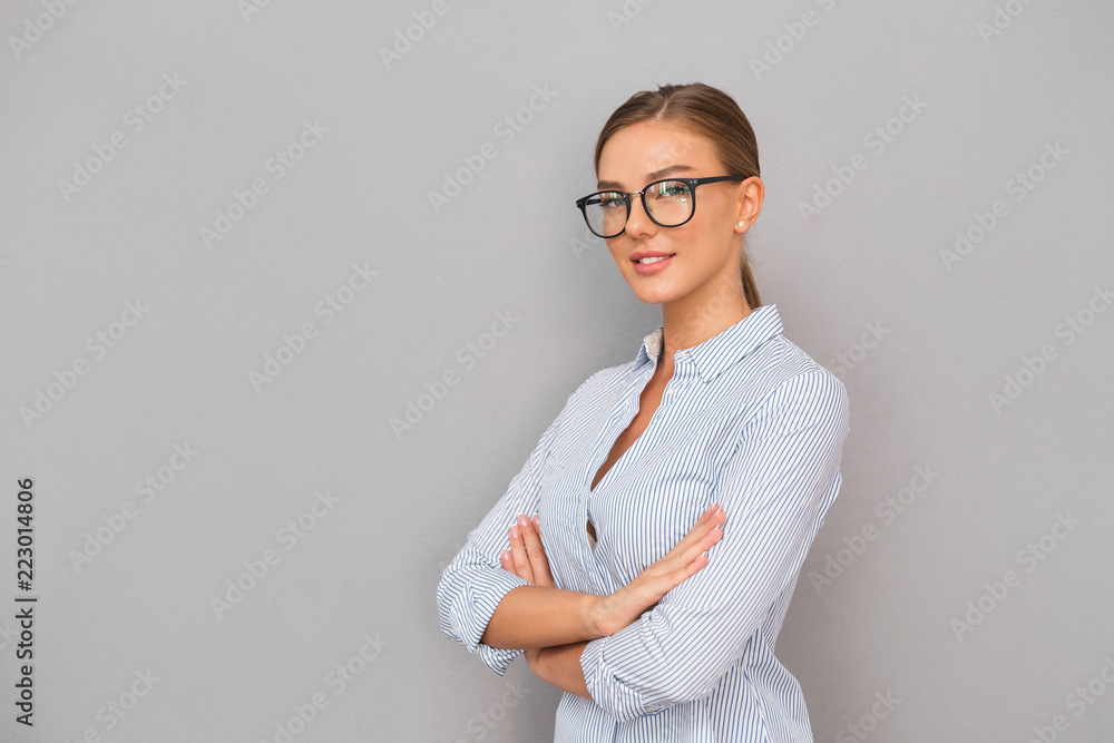 Business woman standing over grey wall background posing. Business woman standing over grey wall background posing.