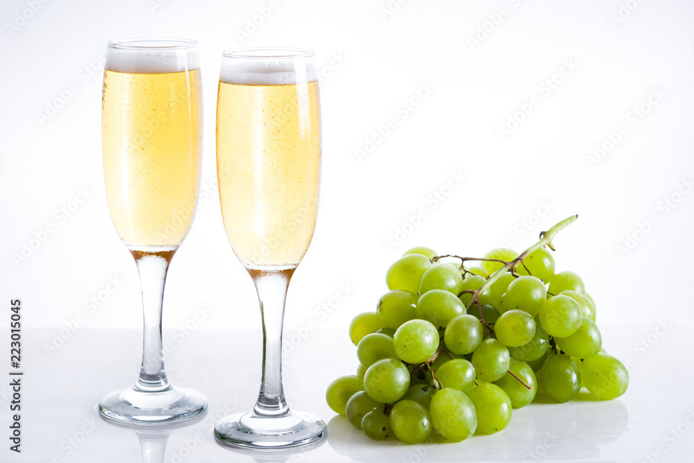 Champagne glasses and green grapes on white background Champagne glasses and green grapes on white background