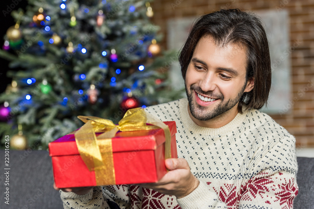 handsome happy man holding christmas present at home handsome happy man holding christmas present at home