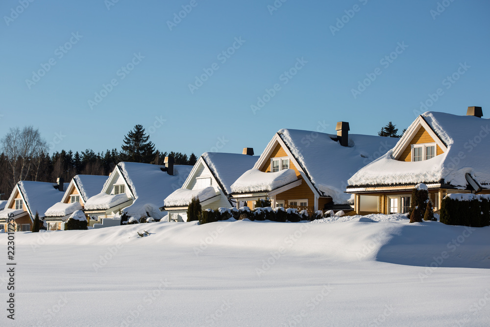 a row of little wooden houses covered with a thick snow layer, deep untouched white snow around