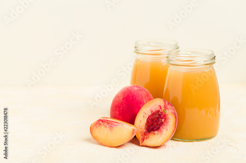 Peach smoothie in glass jars with fresh ripe fruits on yellow pastel background.