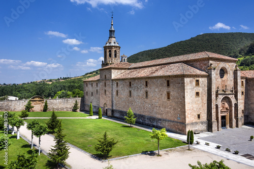 Spain, La Rioja, San Millan de la Cogolla: Panoramic view of famous Monastery of San Millan de Yuso with public park, hills and blue sky. It's the birthplace of modern written spoken Spanish language.