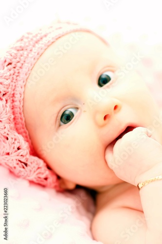 Newborn baby girl posed in a bowl on her back on blanket of fur smiling looking at