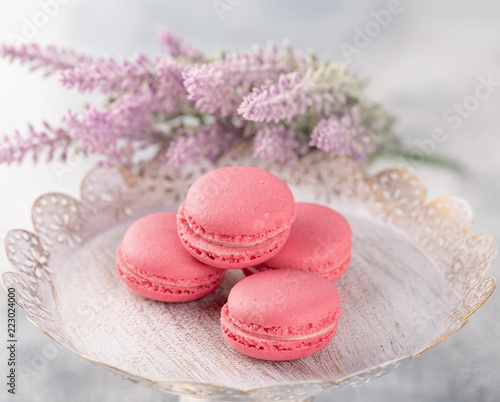 Pink macaroons on a vintage plate and flowers. Pastel colored.