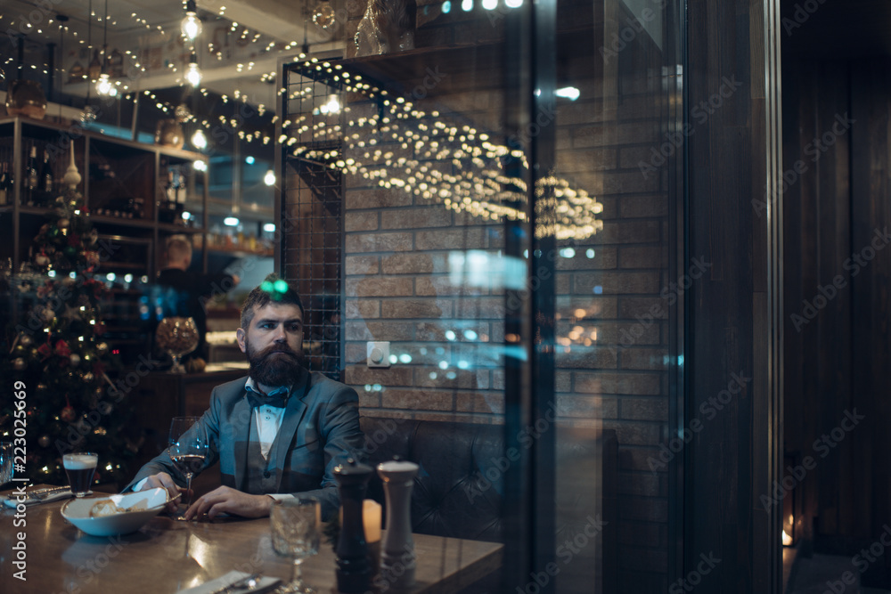 Christmas time of lonely man in bar drinking wine. Christmas party celebration.