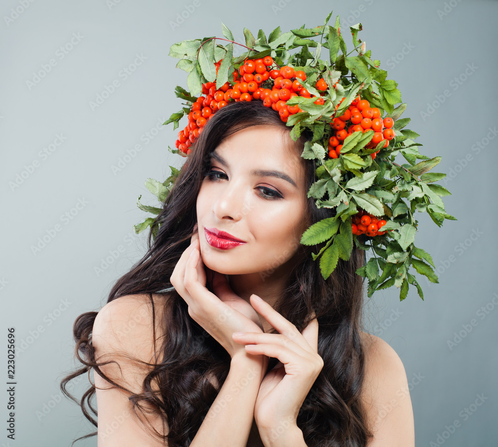 Naklejka premium Young woman brunette with long wavy hair, makeup and autumn berries and leaves wreath