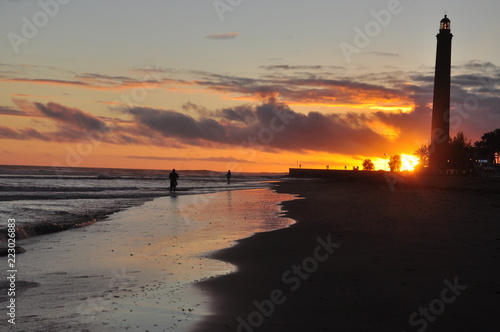 Spectacular sunset at the beach of Maspalomas in National park and sand dunes. Fishermen and famous lighthouse in southern peak of the Gran Canaria island. Canary island