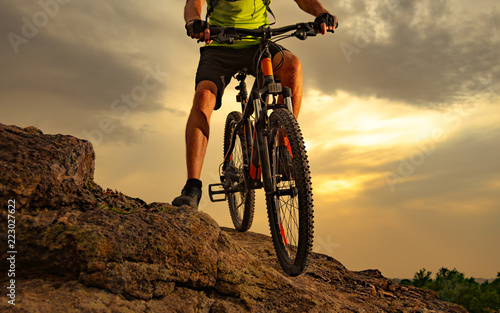 Enduro Cyclist Riding the Mountain Bike on Rocky Trail at Sunset. Close-up of Bicycle. Active Lifestyle Concept.