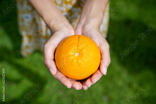 An girl hands present a fresh orange